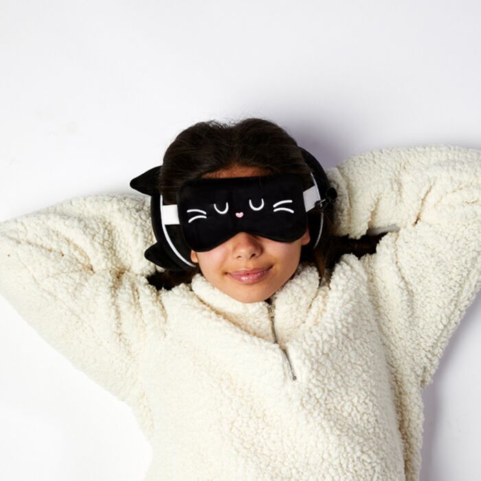 Girl relaxing with plush cat travel eye mask and pillow