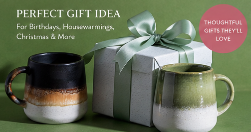 Two ceramic mugs and a gift box with a bow on a green background, promoting thoughtful gifts.