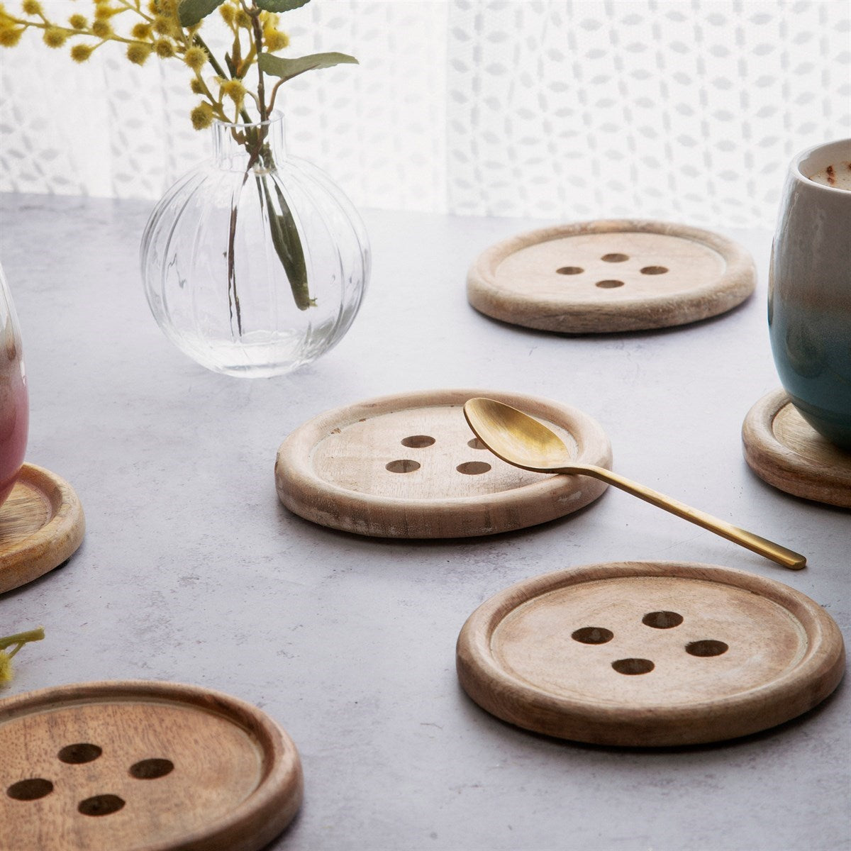 Sass and Belle button coasters styled with mugs on table